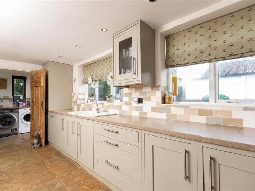 una cucina con mobili bianchi, un lavandino e una finestra di Silver Cottage a Scruton