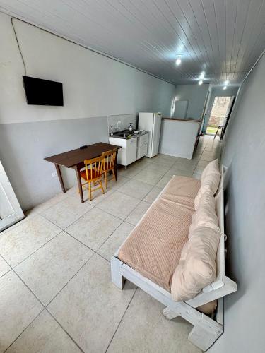 a bedroom with a bed and a kitchen with a table at Kitnet a 150m da praia com Ar Condicionado in Rio Grande