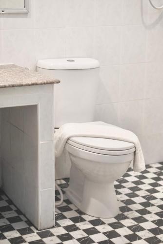 a white toilet in a bathroom with a checkered floor at PK Garden Hotel in Ban Chiang Wang