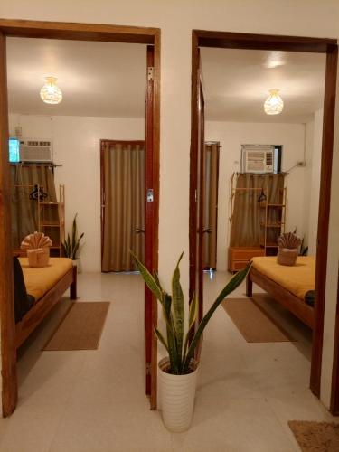 a room with two beds and a potted plant at Kalachuchi Place by Aman Sinaya in General Luna