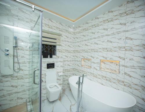 a bathroom with a shower and a toilet and a sink at De Awon's Luxury Hotel in Kasoa