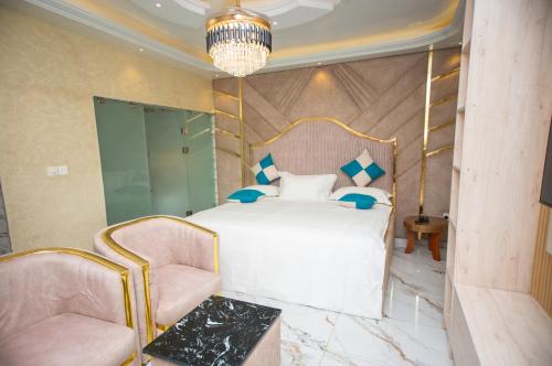 a bedroom with a white bed and two chairs at De Awon's Luxury Hotel in Kasoa