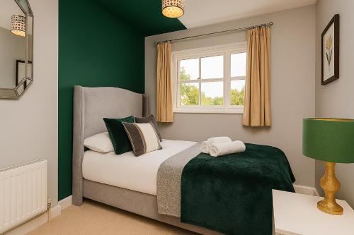 a bedroom with a bed with green walls and a window at Oxford's Most Stylish House - Garden & Parking in Oxford
