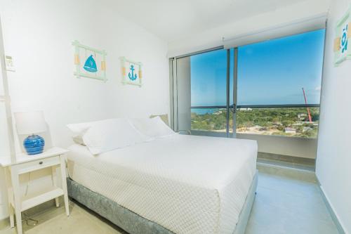 a white bedroom with a bed and a large window at Elemnt Rentals in Santa Marta
