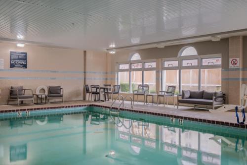 a swimming pool with chairs and tables in a building at Four Points by Sheraton Louisville Airport in Louisville