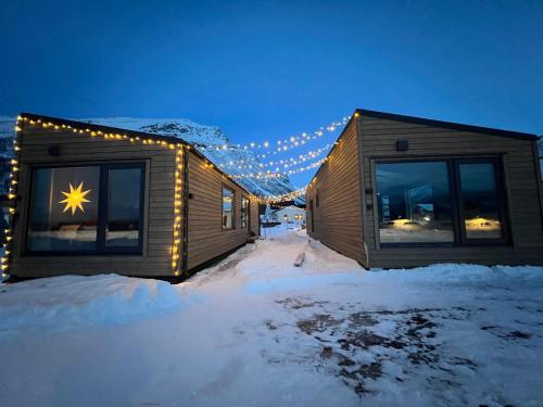 Alpan Apartments, Lyngenfjord في Olderdalen: كوخ في الثلج مع أضواء على النوافذ