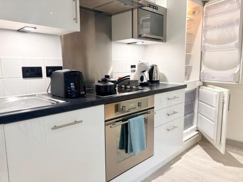 ヨークにあるYork City Centre 2-Bed Apartment with Balcony Views Close to Christmas Marketの白いキャビネットとコンロ付きオーブンを備えたキッチン
