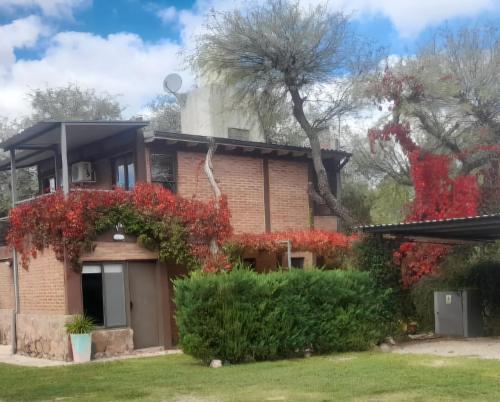 a house with red flowers on the side of it at Cabañas Don Eduardo in Mina Clavero