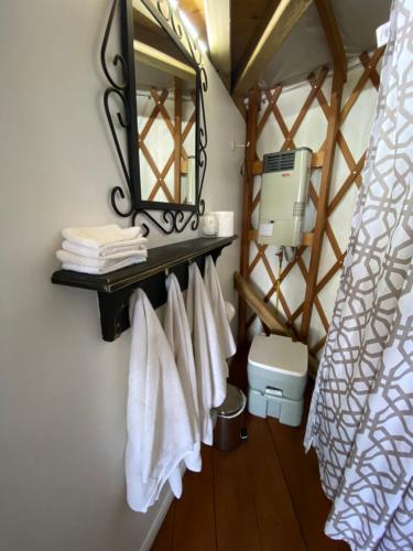 a bathroom with white towels and a mirror at Yourte Forêt des Murmures in Sacré-Coeur-Saguenay