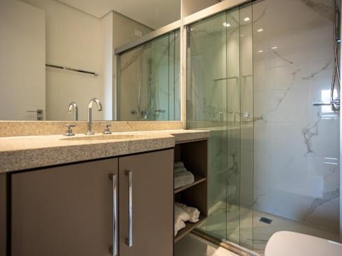 een badkamer met een wastafel en een glazen douche bij Solar Explore Botanico in Curitiba