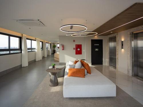 een woonkamer met een witte bank en een tafel bij Solar Explore Botanico in Curitiba