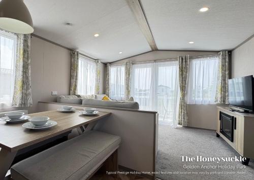 een woonkamer met een tafel en een televisie bij Golden Anchor Holiday Park in Chapel Saint Leonards