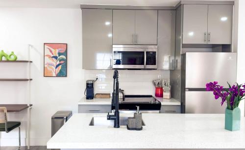 een keuken met witte kasten en roestvrijstalen apparaten bij Cloud Nine - Wilton Drive Jacuzzi Backyard in Fort Lauderdale