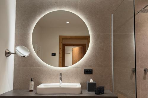 NEW OPENING LA TRUGA Suite Apartments في سيلفا دي فال جاردينا: حمام مع حوض ومرآة على الحائط