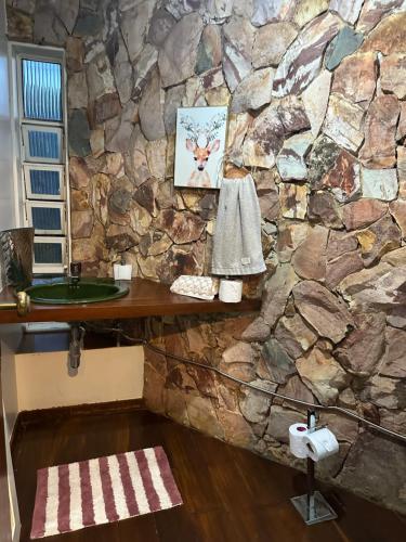 a stone bathroom with a sink and a stone wall at Villa Verde casa espaçosa com piscina e área verde no Lago Norte Brasilia in Brasília