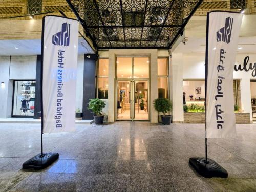 Baghdad Business Hotel - فندق اعمال بغداد في بغداد: لافتتان بيضاوان أمام مبنى