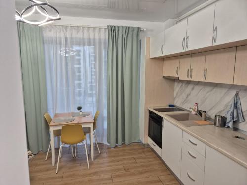 eine Küche mit einem kleinen Tisch, einem Tisch und Stühlen in der Unterkunft Studio Valeria - Promenada Signature , Mamaia Nord in Năvodari