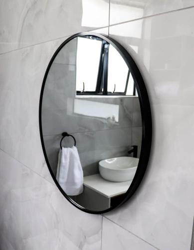 a mirror on a bathroom wall with a sink at Bayley Boutique Guesthouse & Hydro Spa in Benoni