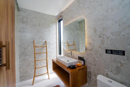 ein Badezimmer mit Waschbecken und Spiegel in der Unterkunft Bali Taoka Villa Tanah Lot in Tanah Lot