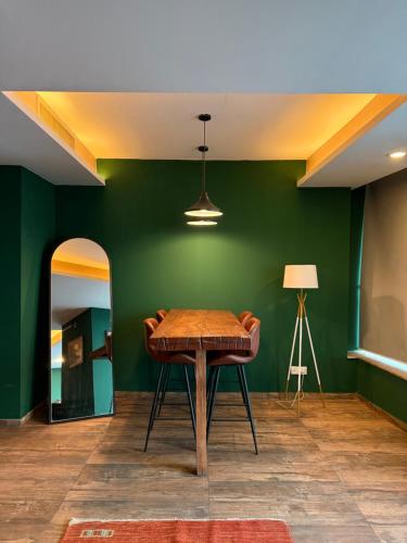 a room with a wooden table and a green wall at 2Bed Apartment in Centaurus with City and Margalla views in Islamabad