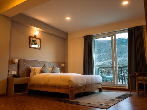 a bedroom with a bed and a large window at Hotel mustang in Jomsom