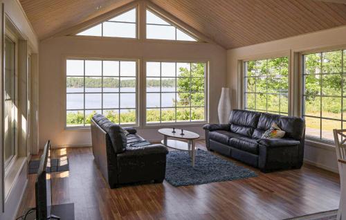 Beautiful Home In Bolmsö With Wifi في Bolmsö: غرفة معيشة مع أريكة وكراسي ونوافذ