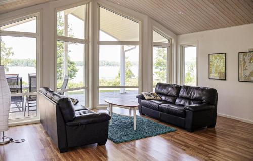 Beautiful Home In Bolmsö With Sauna في Bolmsö: غرفة معيشة مع كرسيين جلديين وطاولة