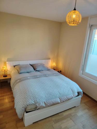 une chambre avec un lit, une fenêtre et un lustre dans l'établissement Au sable fin, à Grand-Fort-Philippe