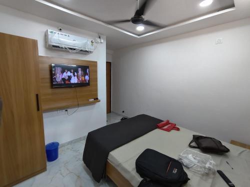 una camera da letto con un letto e una TV a parete di Ishwari Heights a Pandharpur