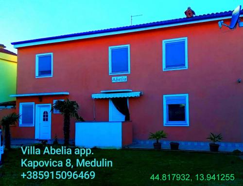 a red house with blue windows in a yard at Villa Abelia in Medulin