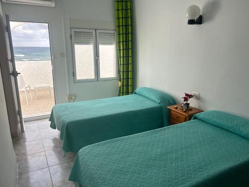 two beds in a room with a view of the beach at El Flamenco in Mojácar