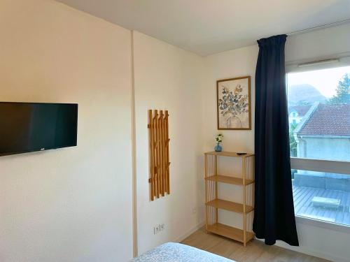 een slaapkamer met een flatscreen-tv en een raam bij Tanière Bleue - OFFER - Clim - Wifi in Lourdes