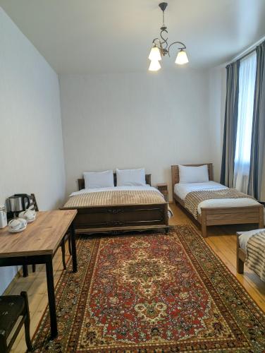 卡兹贝吉Guest house LEGIANA Kazbegi的一间设有两张床、一张桌子和一张地毯的房间