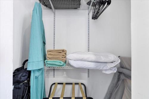 a closet with a shelf with towels and a bag at 5 min to Brickell & Bars - Arcade - King Bed - Outdoor Fun in Miami