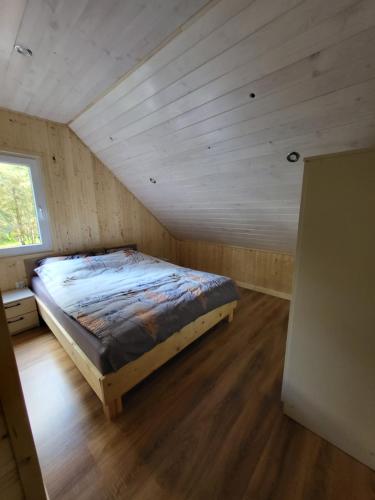 Domek nad jeziorem Wilczyńskim في Świętne: سرير في غرفة ذات سقف خشبي