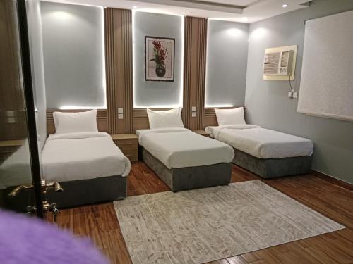 een kamer met 2 bedden en een tapijt bij شقق المتميزين in Al Madinah