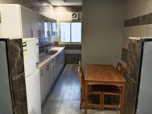 een keuken met een houten tafel en een tafel met stoelen bij شقق المتميزين in Al Madinah