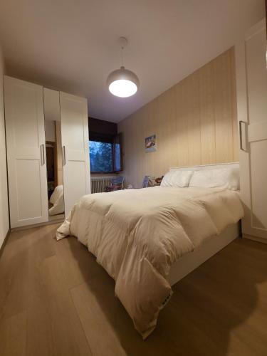 ein Schlafzimmer mit einem großen Bett mit weißer Bettwäsche in der Unterkunft Hope Home Trentino in San Martino di Castrozza