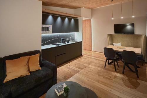 NEW OPENING LA TRUGA Suite Apartments في سيلفا دي فال جاردينا: غرفة معيشة مع أريكة وطاولة ومطبخ