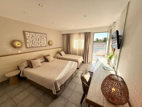 Un dormitorio con dos camas y una mesa y un televisor. en Hôtel Restaurant L' Empereur, en Aléria