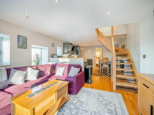 Yr Hen Beudy في Tregaron: غرفة معيشة مع أريكة أرجوانية ودرج