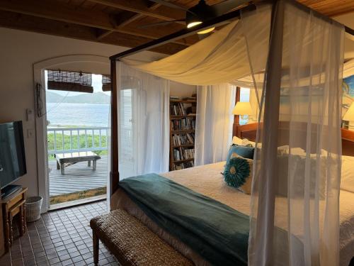 Schlafzimmer mit einem Himmelbett und Meerblick in der Unterkunft Blue Pearl Villa in St John USVI in Coral Bay