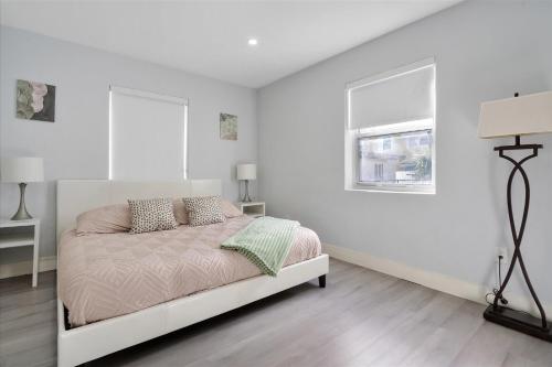 a white bedroom with a bed and a window at 5 min to Brickell & Bars - Arcade - King Bed - Outdoor Fun in Miami