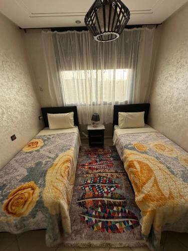 Un dormitorio con dos camas y una ventana. en Oumhani5, en Sale