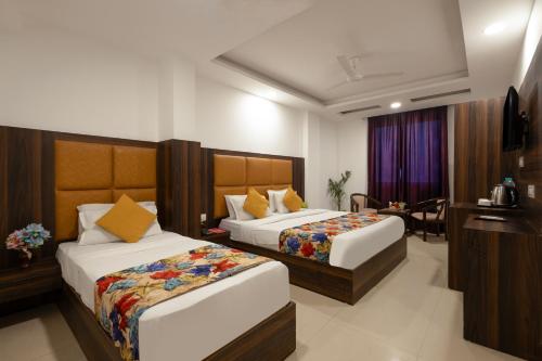 a hotel room with two beds and a desk at Hotel Claytone Near Delhi Airport in New Delhi