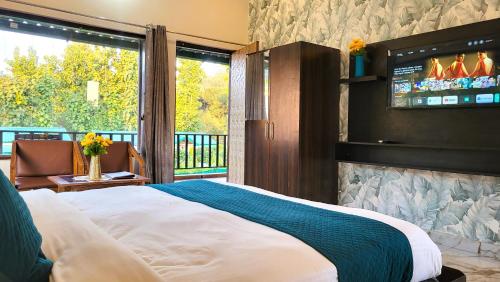 ein Schlafzimmer mit einem Bett und einem Fernseher an der Wand in der Unterkunft Corbett Nature Walk - Forest View Swimming Pool in Rāmnagar
