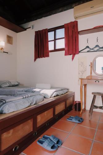 two beds in a room with flip flops on the floor at A Touch of Zen in Kaohsiung