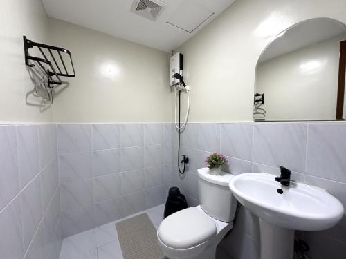 a white bathroom with a toilet and a sink at Meraki Space Mactan Cebu in Lo-oc