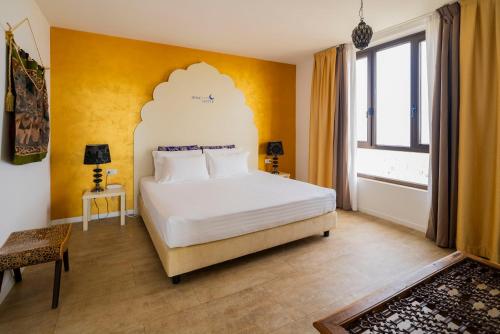 PianoB - Breakfast Hotel & Bar في سينِغاليا: غرفة نوم بسرير ابيض وجدار اصفر