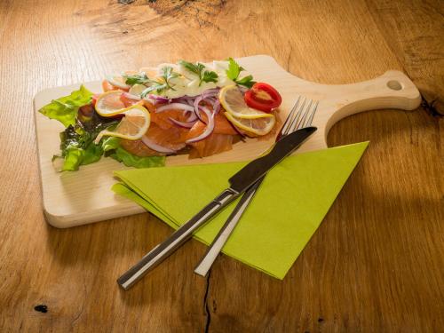 a plate of food on a wooden table with a fork and knife at Siri's Einkehr in Sankt Georgen im Attergau
